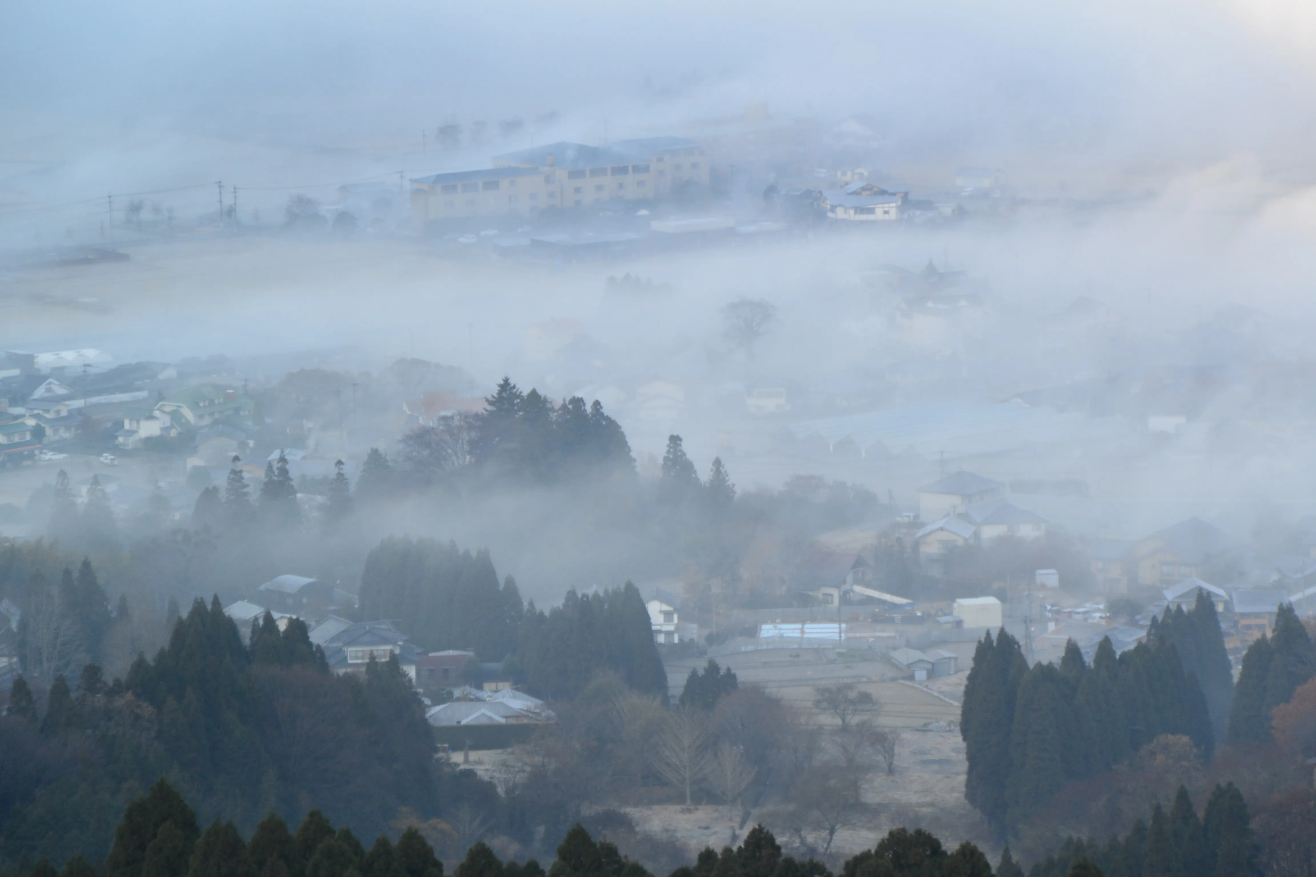 Yufuin town under morning fog, with the ridge of Mount Yufu showing above the mist