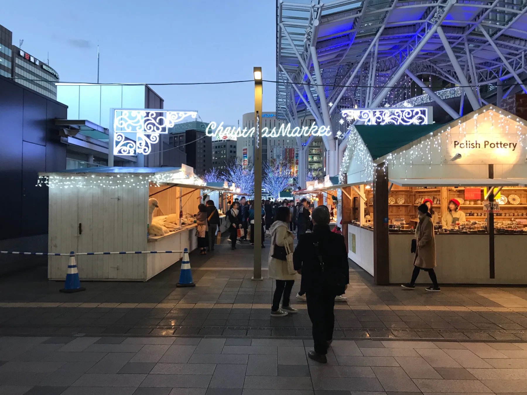 Wooden market stalls and crowds under the Christmas lights in the plaza in front of JR Hakata Station