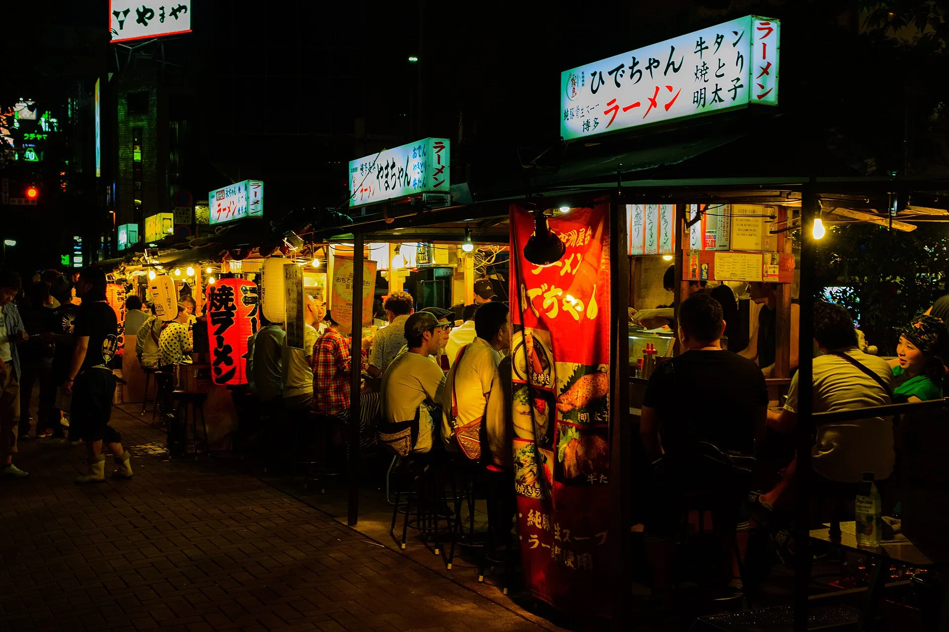 夜に灯りがともった中洲の川沿いの屋台の列